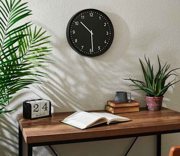 a desk with a book and a clock on the wall